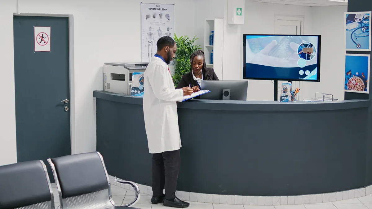 Doctor and receptionist reviewing patient records on HIPAA-compliant computer system